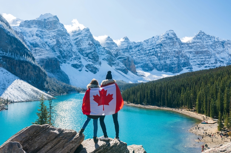 Two people holding Canadian flag at Moraine Lake, Banff, AB