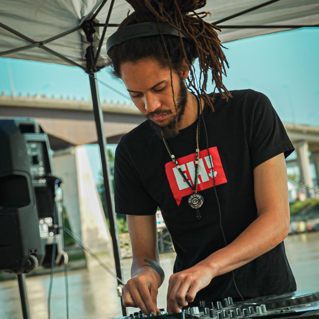 DJ performing at outdoor event wearing EH! shirt